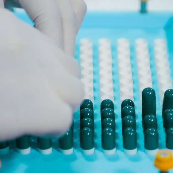 Gloved hands arranging capsules on a pharmaceutical production tray, representing Indian generic drug manufacturing