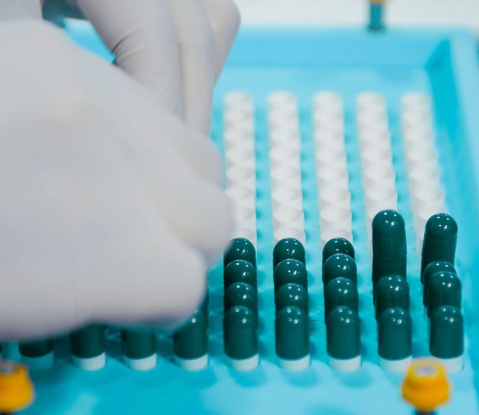 Gloved hands arranging capsules on a pharmaceutical production tray, representing Indian generic drug manufacturing