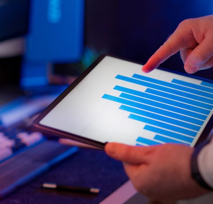 Business professional analyzing bar chart data on a tablet, representing pharma brand manager reviewing digital marketing analytics