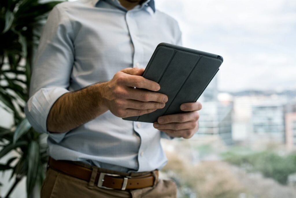 Pharma Field Force Effectiveness Metrics: 12 to Track, 5 to 2 Field sales professional reviewing data on a tablet near a city window, representing an MR accessing CRM metrics in the field