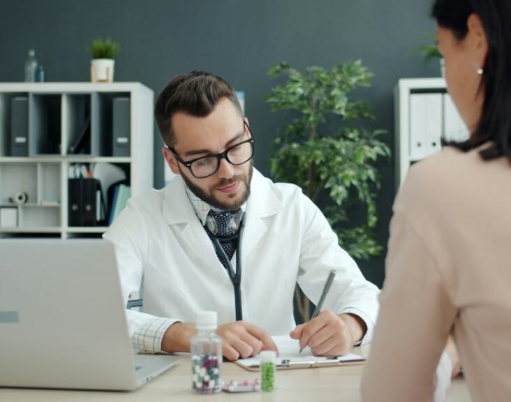 Doctor consulting at clinic desk with medication — representing the MR-HCP interaction at the heart of medical representative training