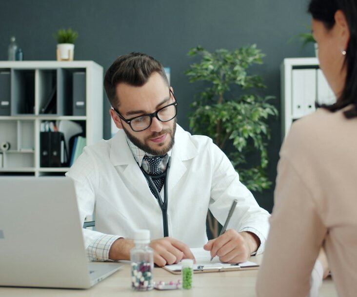 Doctor consulting at clinic desk with medication — representing the MR-HCP interaction at the heart of medical representative training