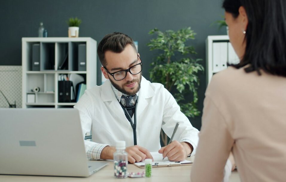 Doctor consulting at clinic desk with medication — representing the MR-HCP interaction at the heart of medical representative training
