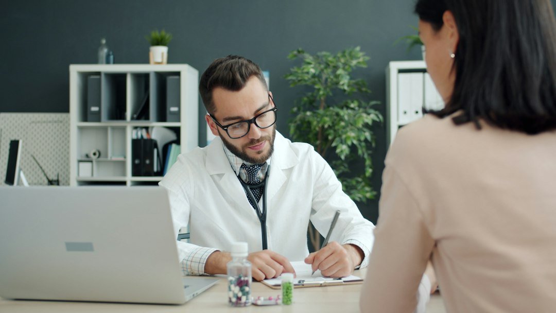 Doctor consulting at clinic desk with medication — representing the MR-HCP interaction at the heart of medical representative training