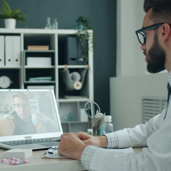 Doctor in white coat engaging in a digital video consultation on a laptop, representing omnichannel HCP engagement in pharma