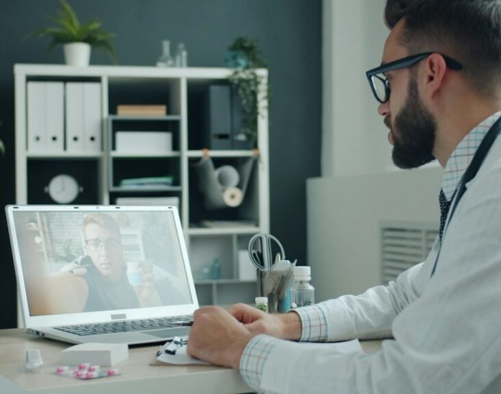 Doctor in white coat engaging in a digital video consultation on a laptop, representing omnichannel HCP engagement in pharma