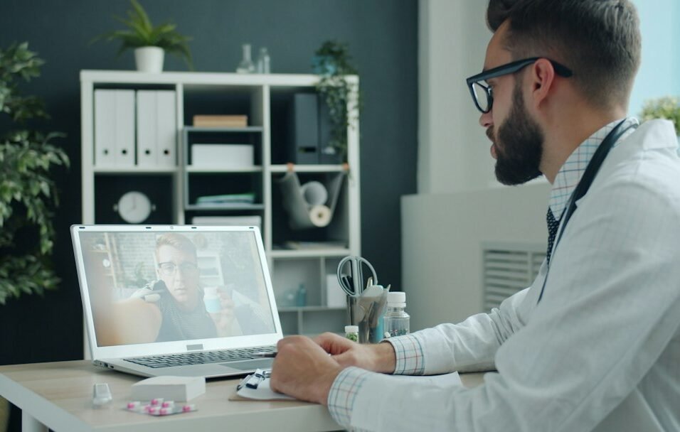 Doctor in white coat engaging in a digital video consultation on a laptop, representing omnichannel HCP engagement in pharma