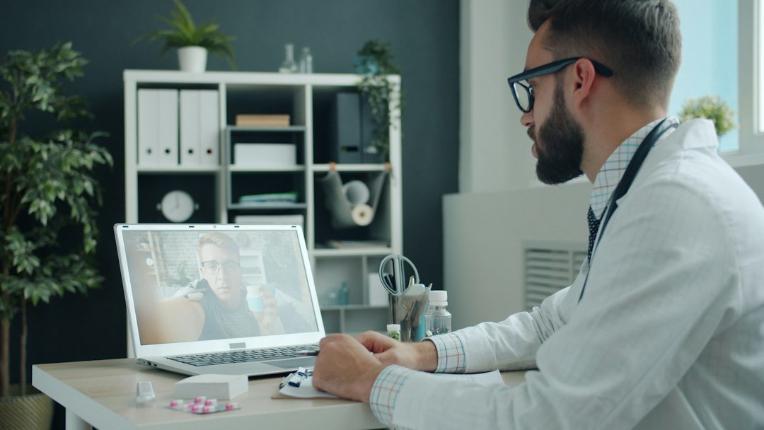 Doctor in white coat engaging in a digital video consultation on a laptop, representing omnichannel HCP engagement in pharma